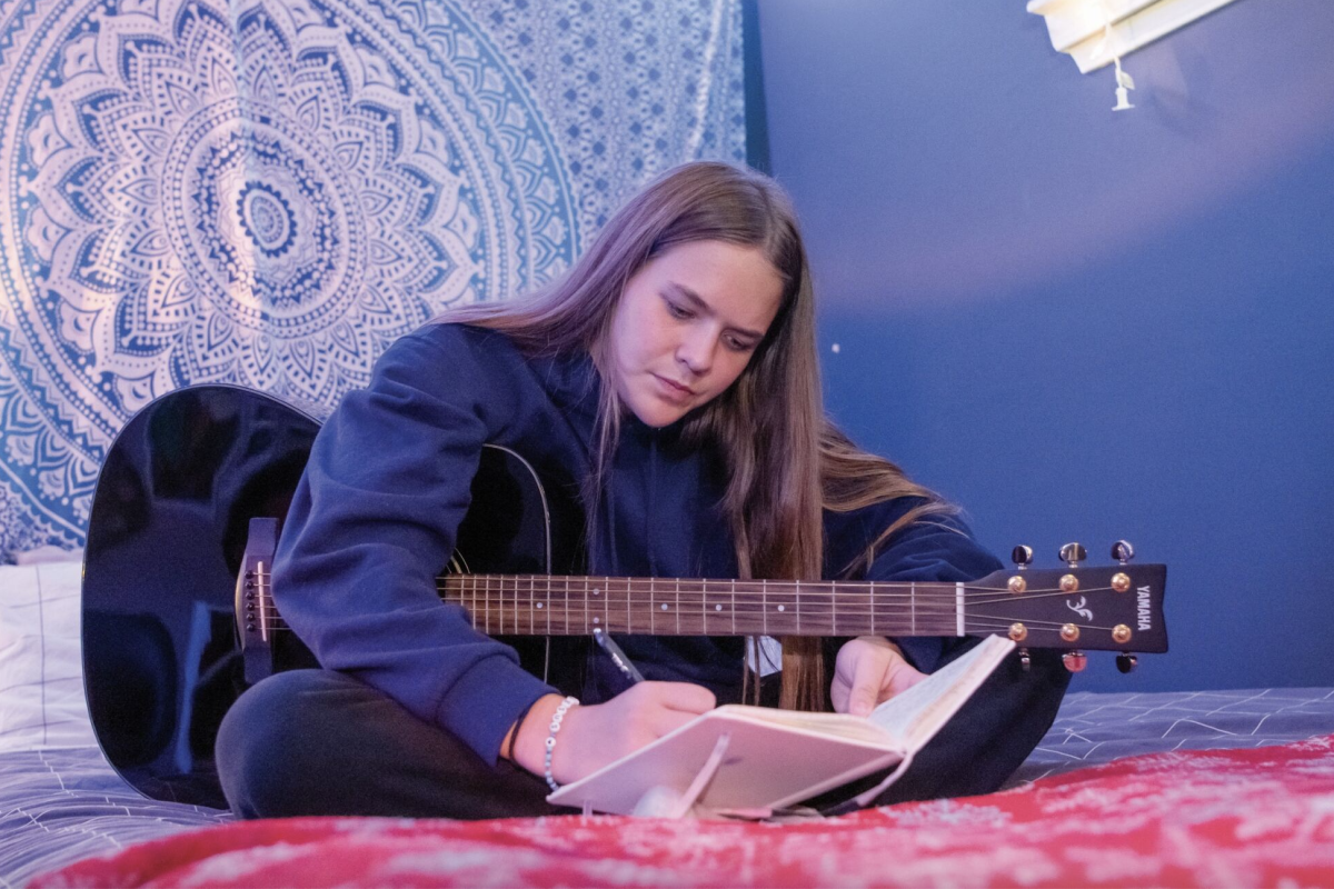 Finding inspiration, junior Addy Baker writes down lyrics Oct. 25 in her room. Baker writes in her room for privacy. “My room is a safe place for me,” Baker said. “It’s where I can be vulnerable and I feel like the environment helps me be a more creative writer.”
